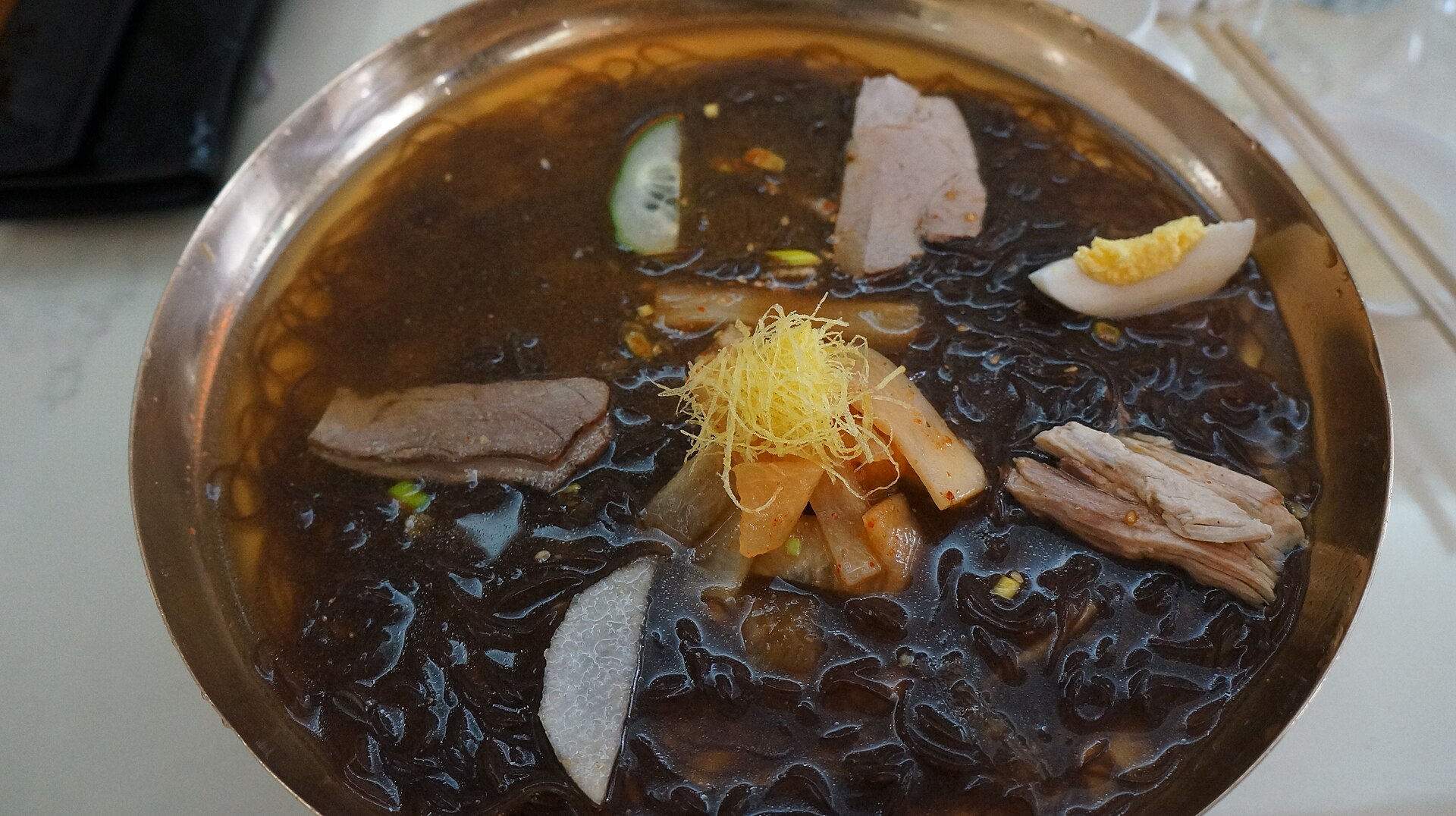 맑은 육수에 메밀 면과 고명을 담은 평양식 냉면