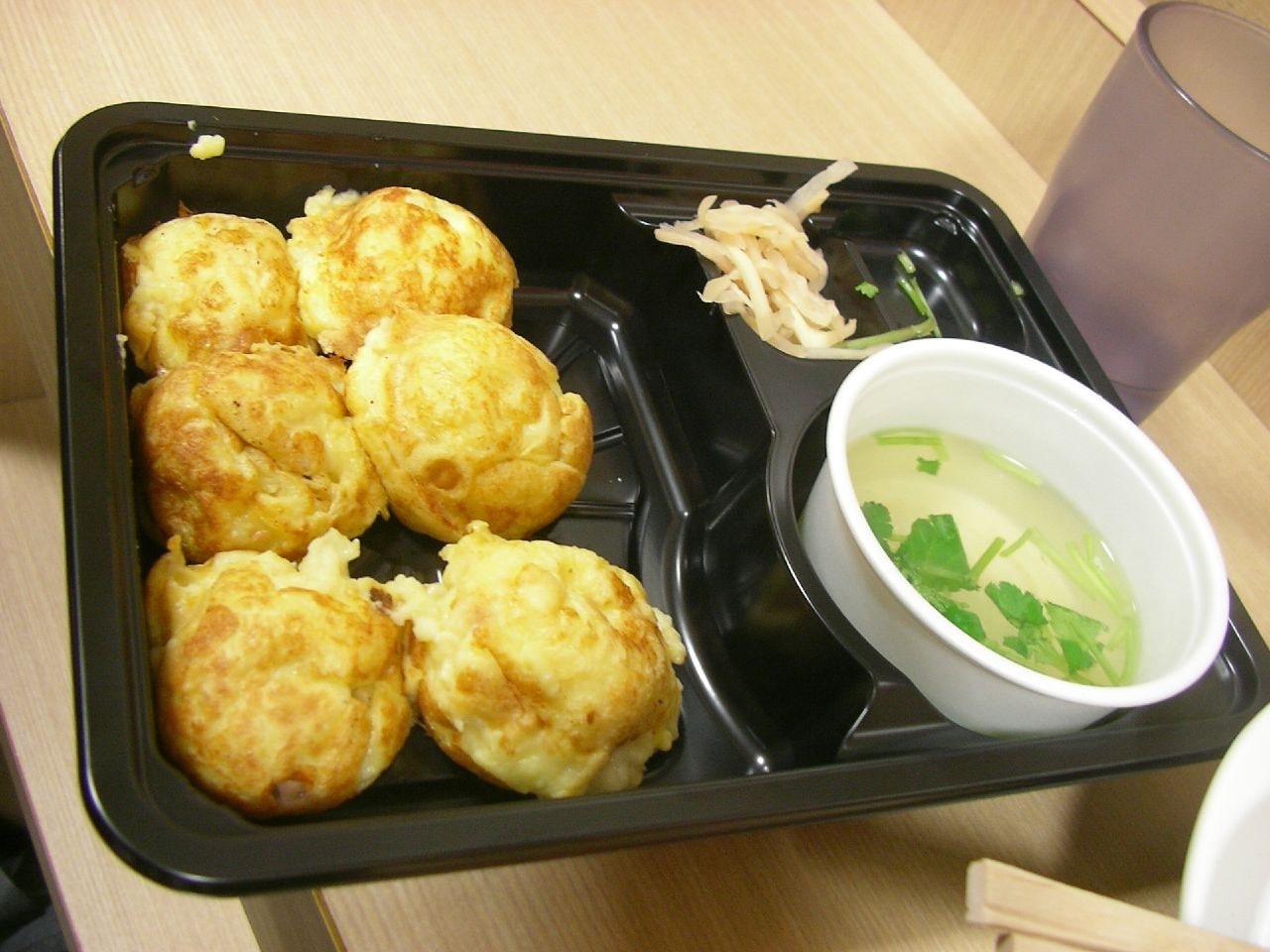 검은 쟁반 위 노란 아카시야키 여섯 알과 별도 컵에 담긴 맑은 장국
