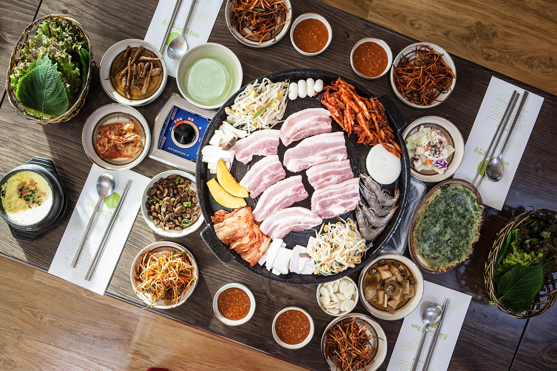 삼겹살과 쌈채소, 반찬이 놓인 식탁