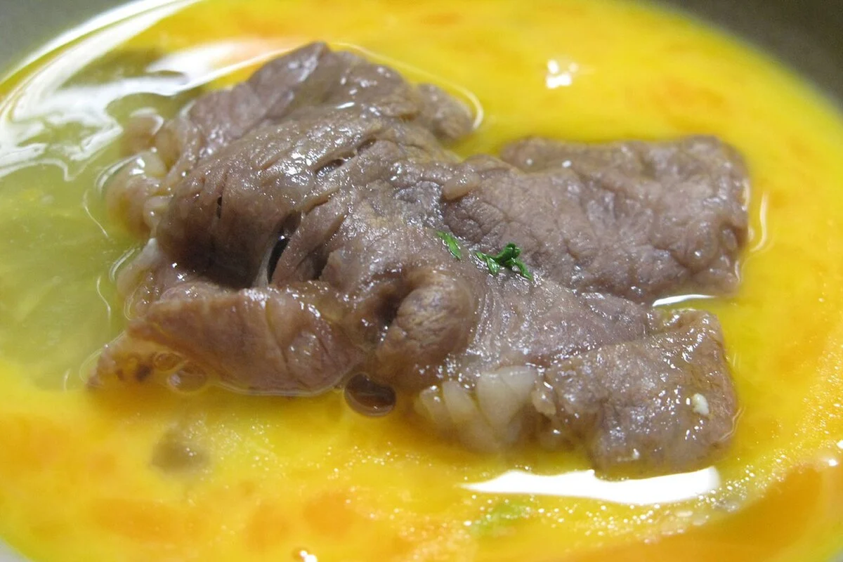 간장 양념이 밴 스키야키 소고기를 풀어 놓은 날달걀에 담근 모습
