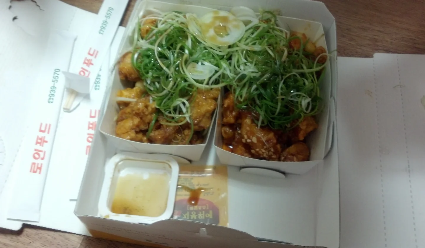 두 칸 포장 상자의 치킨 위에 초록색 파채를 수북하게 올린 파닭