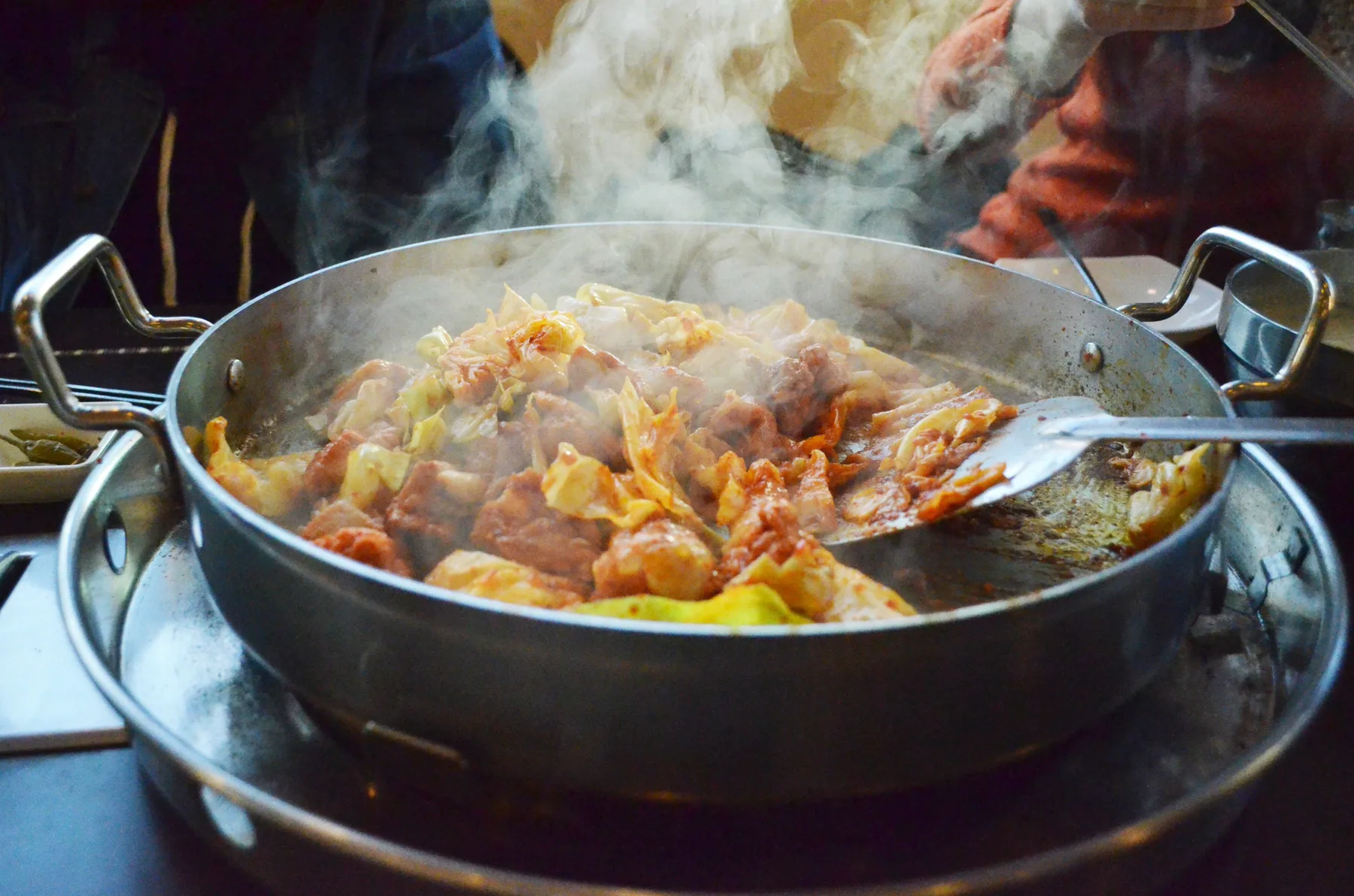 김이 오르는 둥근 철판에서 붉은 닭갈비를 볶는 모습