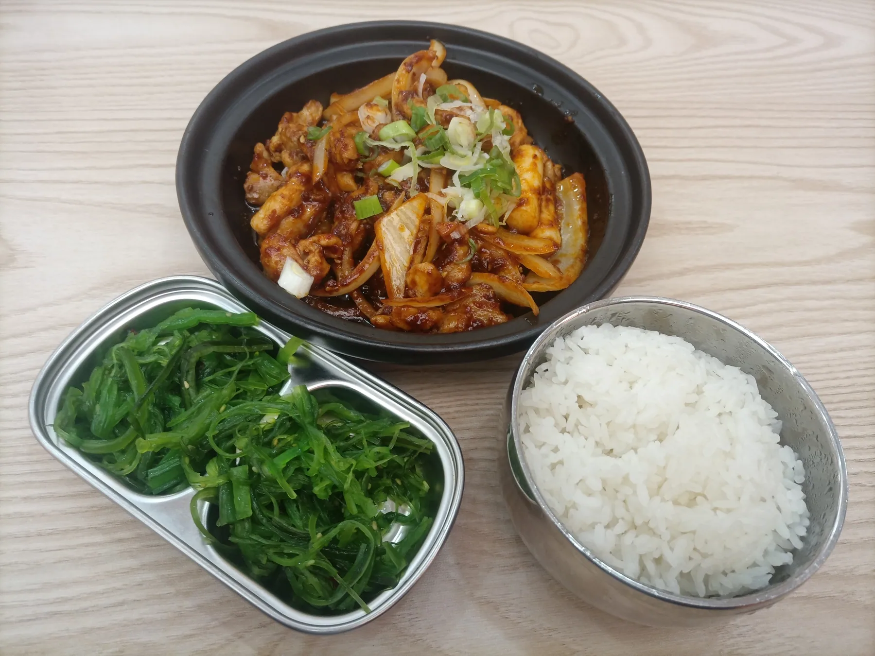 볶은 닭갈비와 흰밥, 초록 해조류 반찬을 나란히 담은 상차림