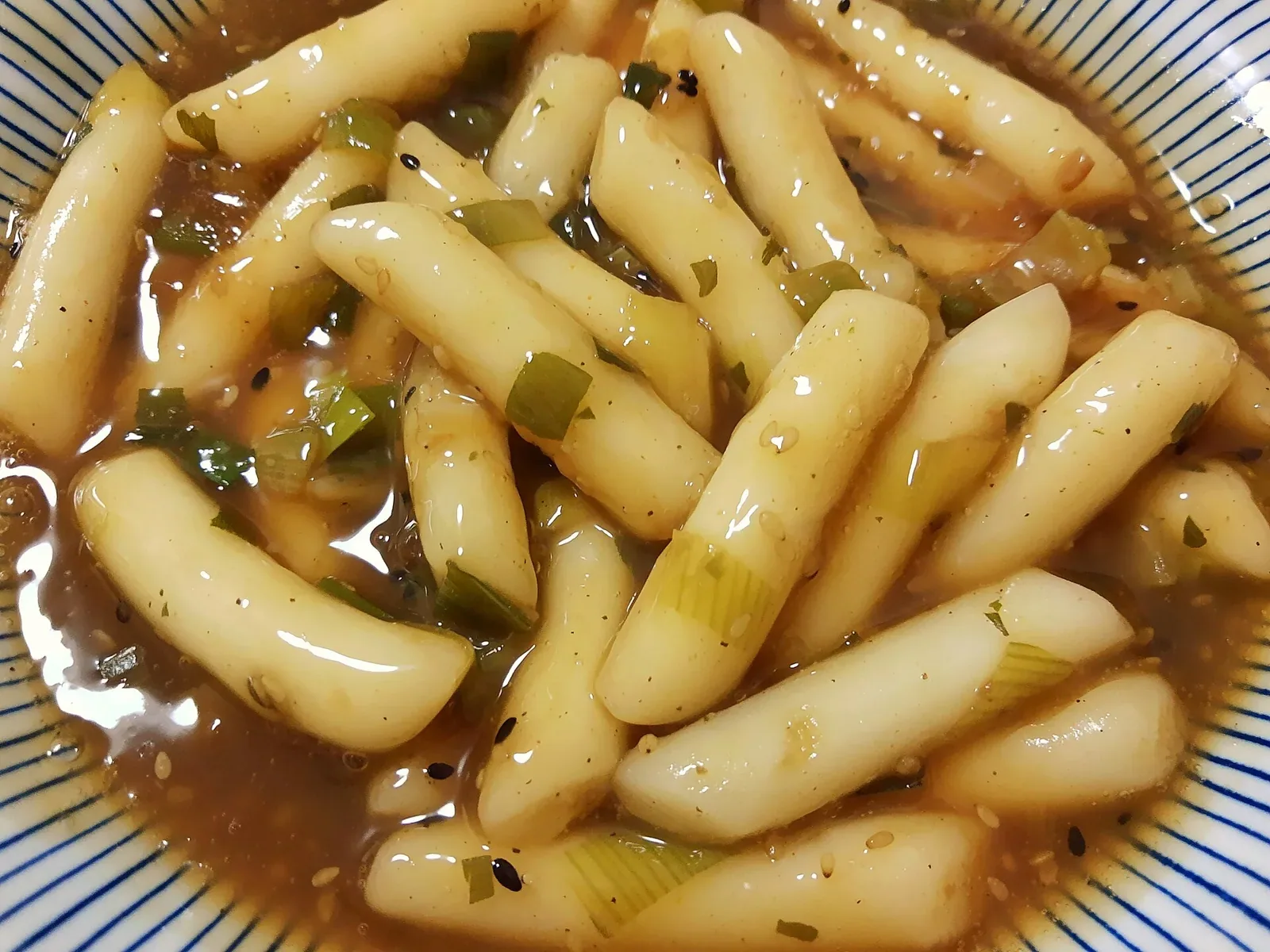 길쭉한 떡과 파가 갈색 간장 양념에 담긴 간장떡볶이
