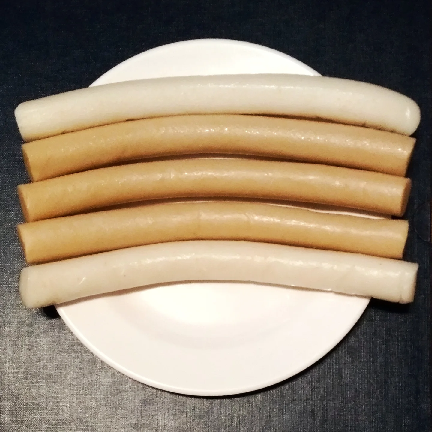 흰 접시에 흰 가래떡 두 줄과 갈색 메밀 가래떡 세 줄을 나란히 놓은 모습