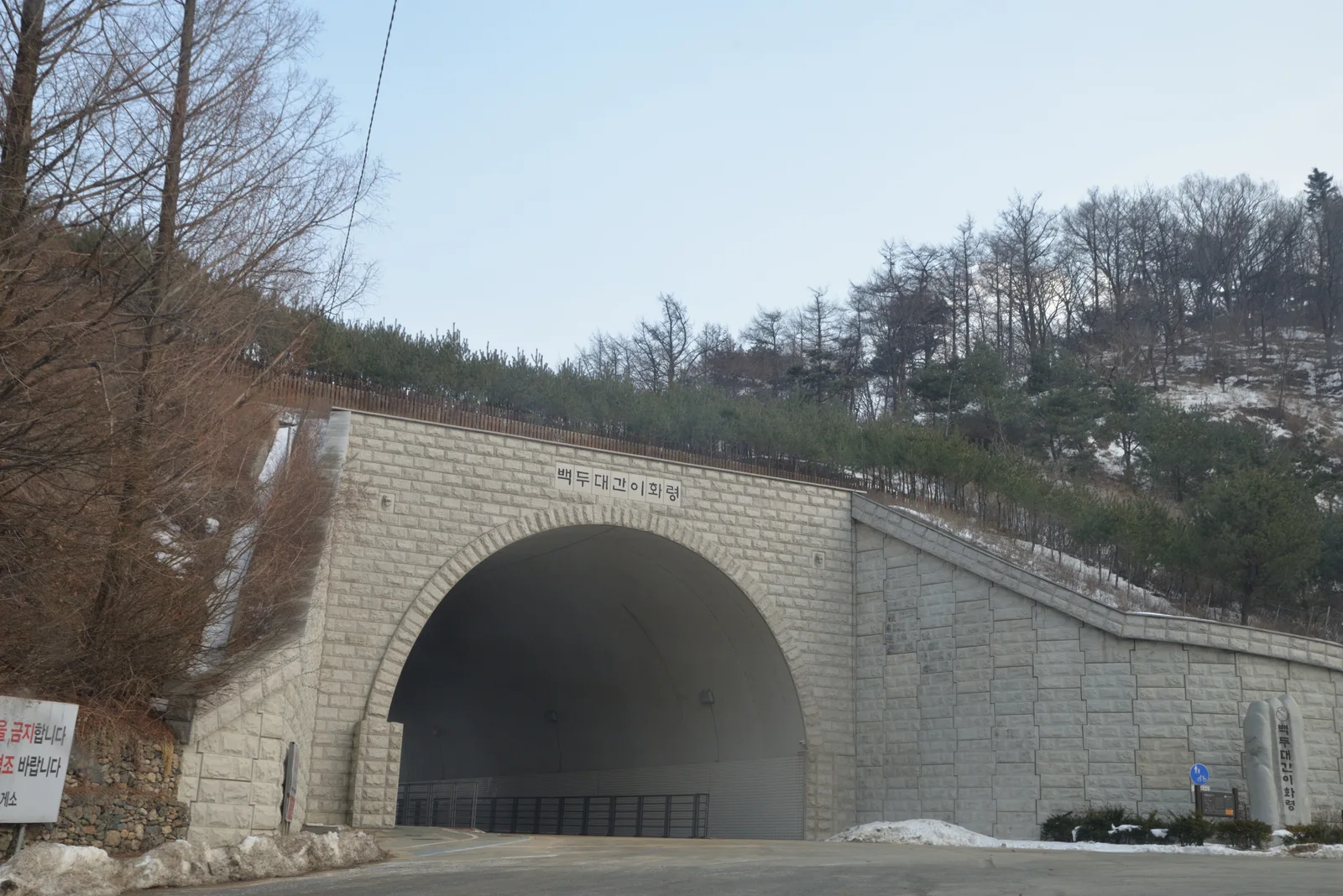 눈이 남은 이화령의 도로 터널과 그 위를 덮은 산비탈