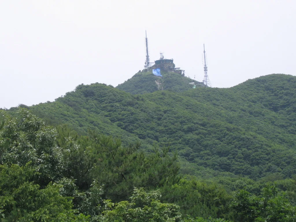 숲으로 덮인 모악산 정상부 위로 보이는 방송시설과 철탑